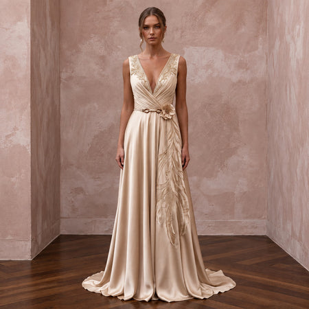 Champagne silk charmeuse maxi dress with plunging neckline and floral embroidery detail. Elegant and flowing design.