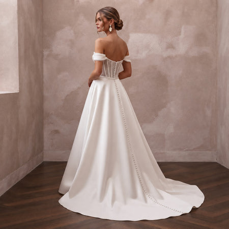 Off-the-shoulder satin wedding gown with corset back and chain-trim detail