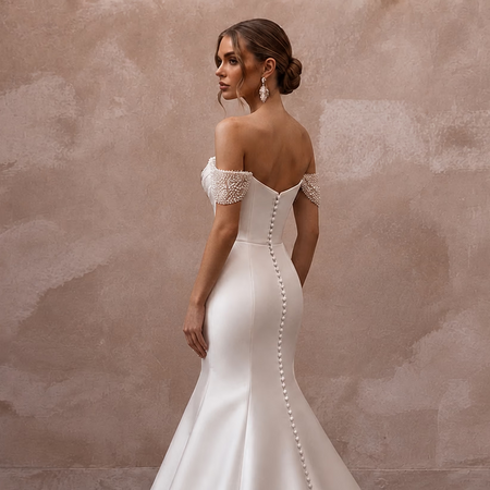 White satin off-the-shoulder wedding dress with lace shoulder caps and pearl back ties