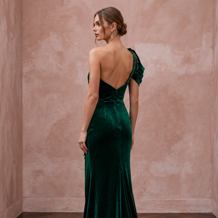 Emerald green velvet one-shoulder formal gown featuring an asymmetrical design and elegant ruffle detail.