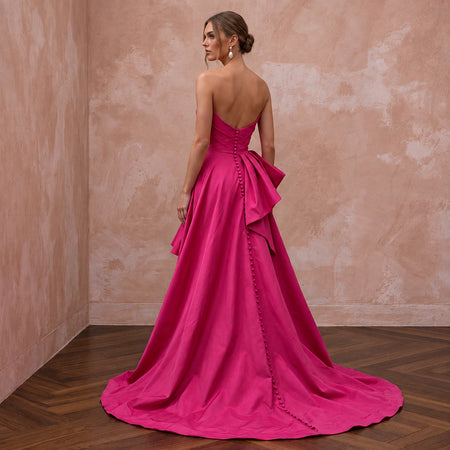 Fuchsia pink taffeta strapless dress with high-low hem and elegant bow detail, perfect for summer events.