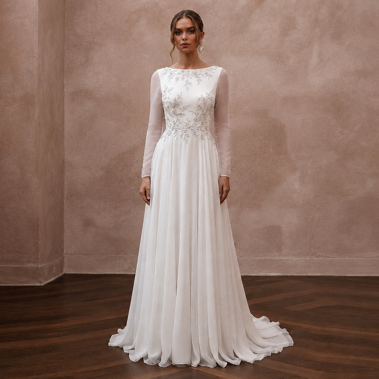 A woman stands in a studio wearing a long-sleeve white wedding gown with an embellished lace bodice and a flowing chiffon skirt, posed against a textured beige wall and dark wood floor. Main image