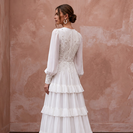 Elegant pure white chiffon gown featuring tiered skirt and long sleeves, adorned with intricate beadwork.