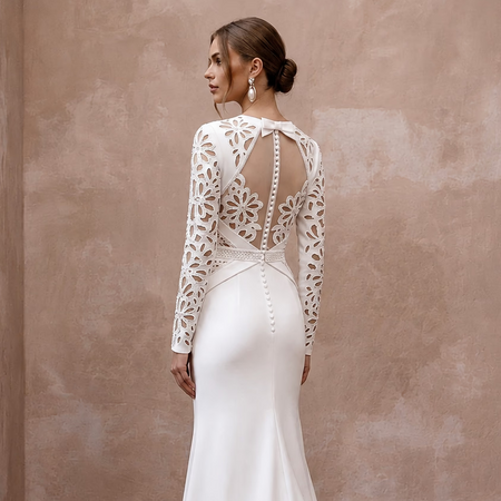 White satin wedding dress with long lace sleeves and open back featuring draped straps
