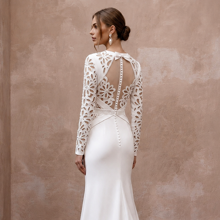 White satin wedding dress with long lace sleeves and open back featuring draped straps