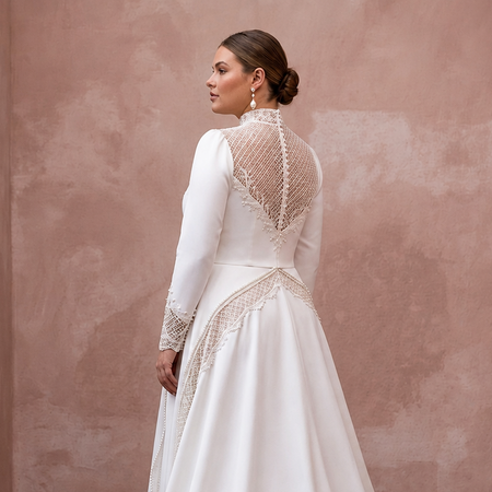 White satin wedding dress with lace back yoke, long sleeves, and draped train