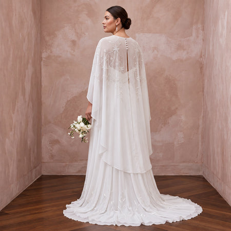 Plus size pure white silk chiffon bridal gown with draped capelet and floral embellishments, perfect for weddings.