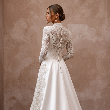 Satin wedding dress with lace illusion back, long sleeves, and buttoned open-back detail