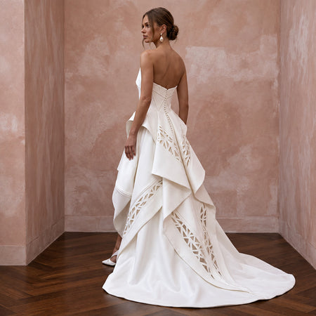 Sculptural white Mikado silk dress with high-low hem and architectural detailing, perfect for modern occasions.