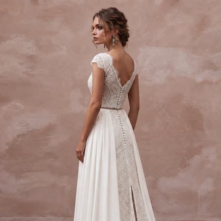 Elegant sweep train boho bridal gown with lace bodice and side slit, perfect for a destination wedding.